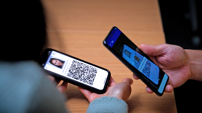 A person using a phone to scan a QR code on another phone.